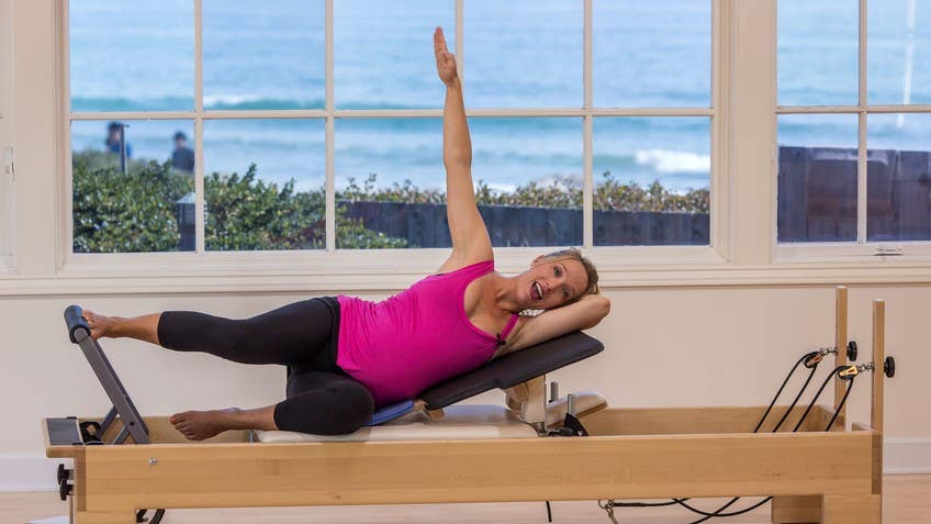 Woman doing short spine pilates exercises on a reformer bed in a